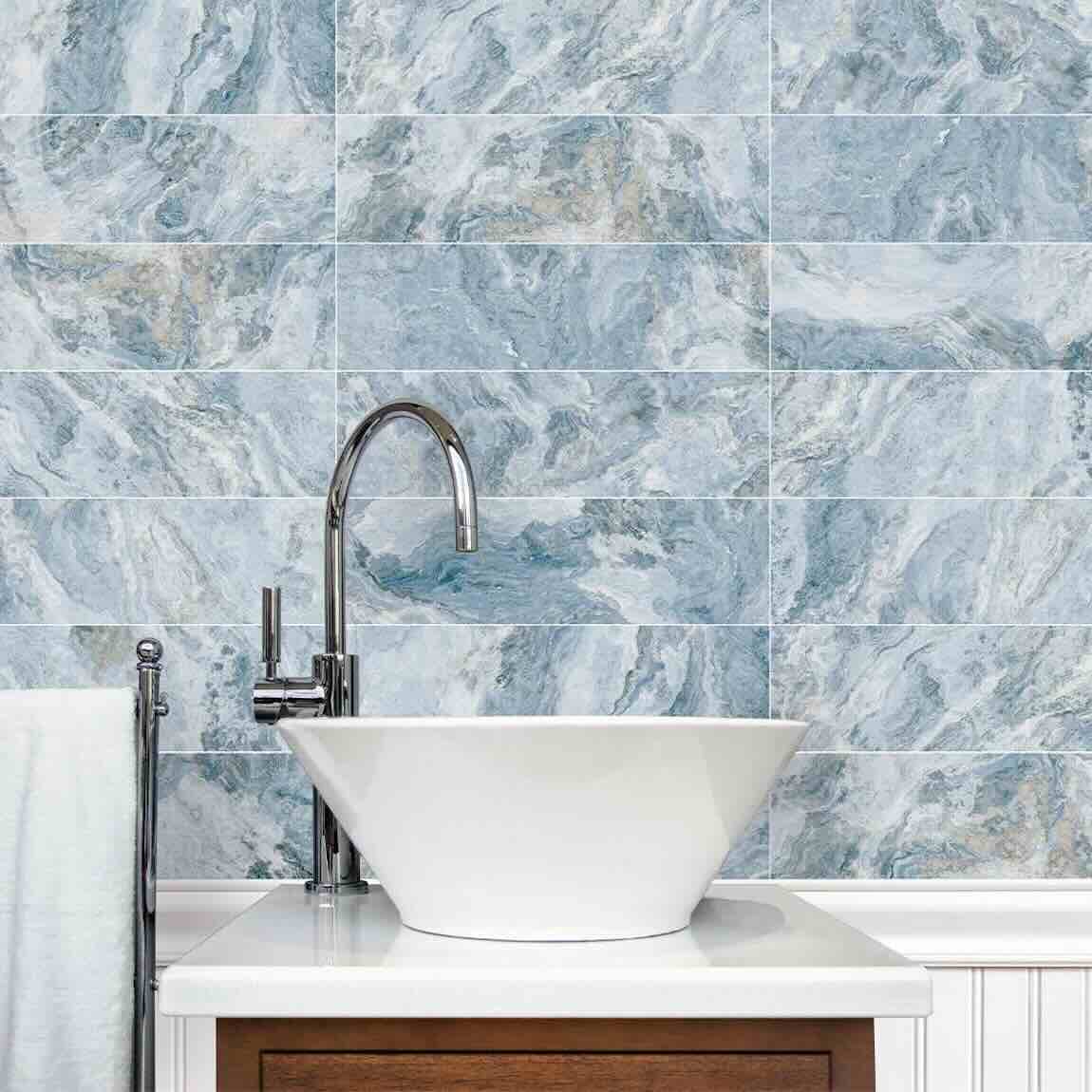 Bathroom with a white sink and silver faucet against a blue marble tile wall.