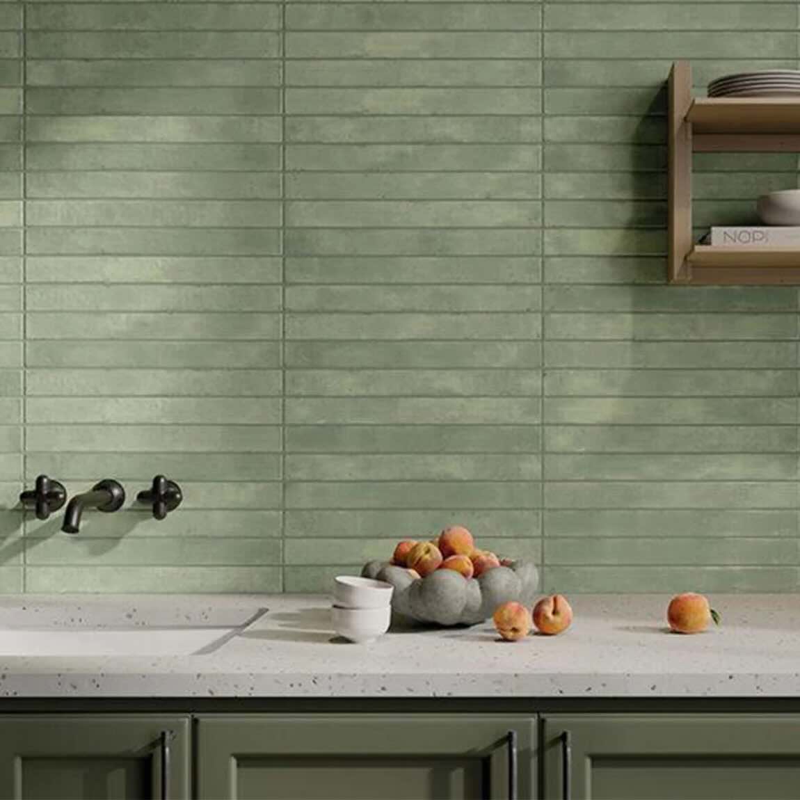 Kitchen with green tiled brick wall, marble countertop, and decorative fruit bowl.