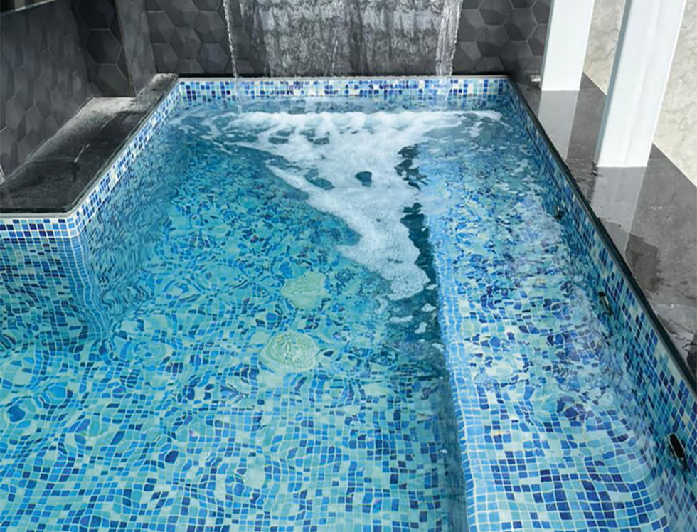 Recycled glass tile in Water Blend, installed in a pool to deliver a sustainable and sparkling surface with blended aqua, blue, and teal tones that mimic natural water movement.”