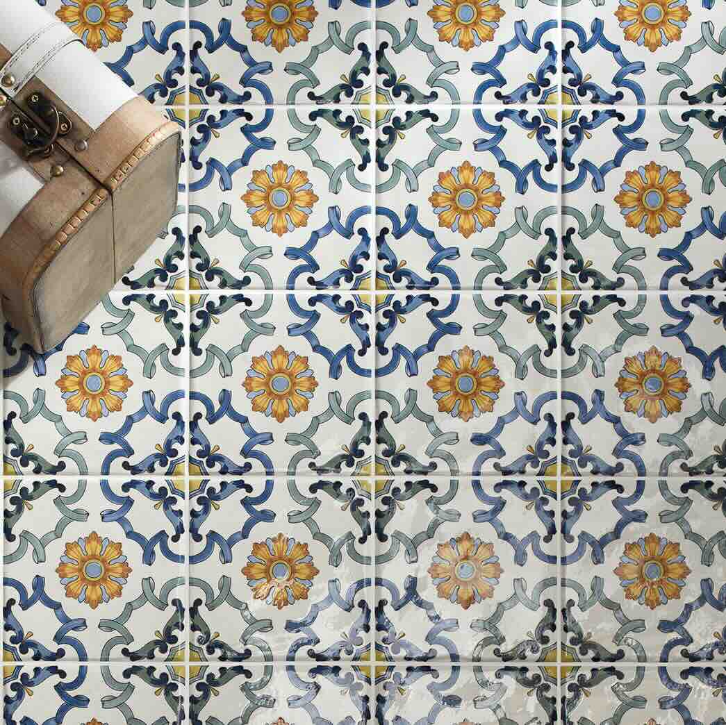 Patterned tiles with floral designs in blue, yellow, and white on a floor.