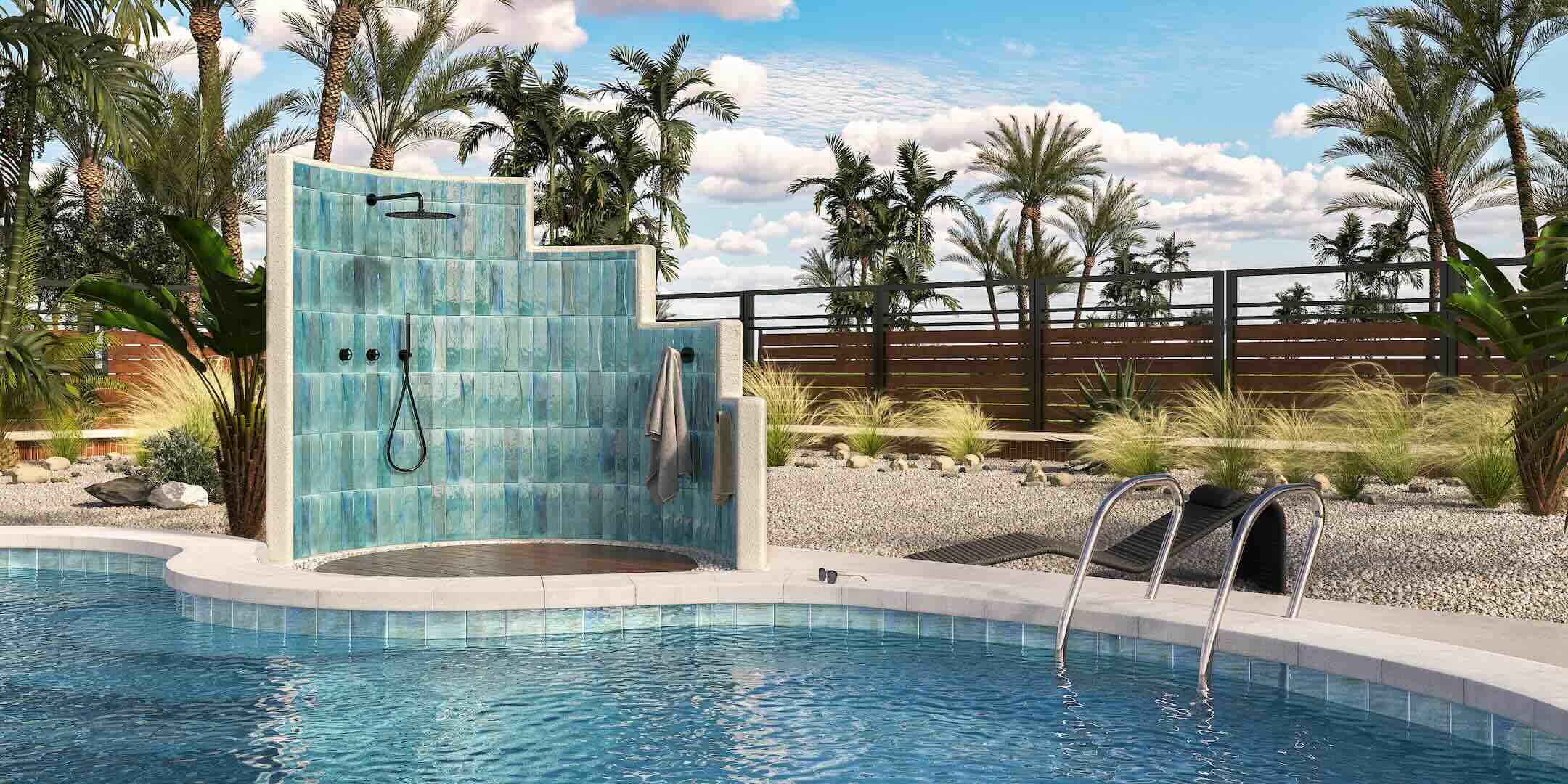 Outdoor shower with blue tiles by a pool, surrounded by palm trees and greenery.