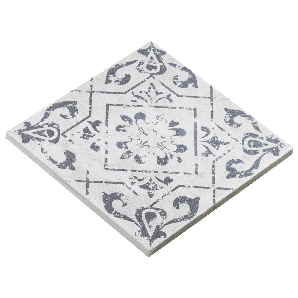 Detailed look at a decorative 6x6 vintage-style tile in a weathered white tone with blue floral motifs.