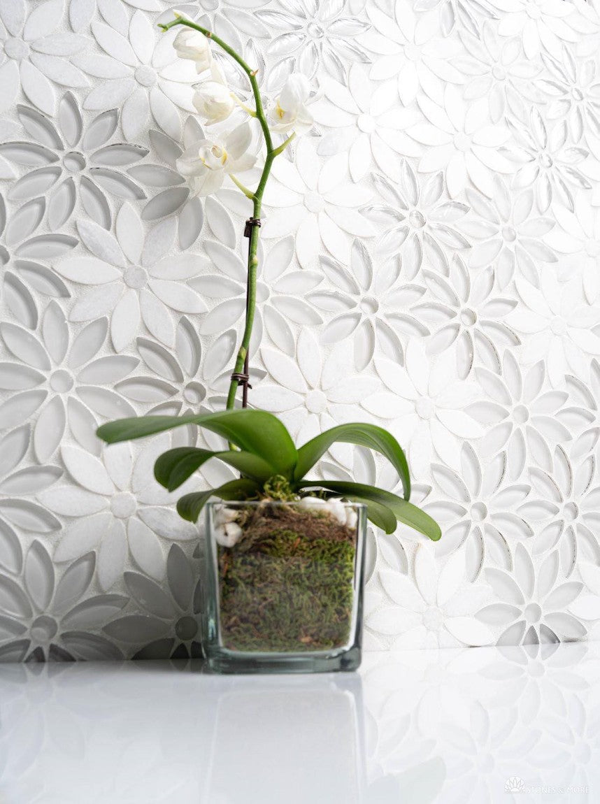 White orchid in front of a backsplash made of Arctic Waterjet Flower Mosaic Tile.