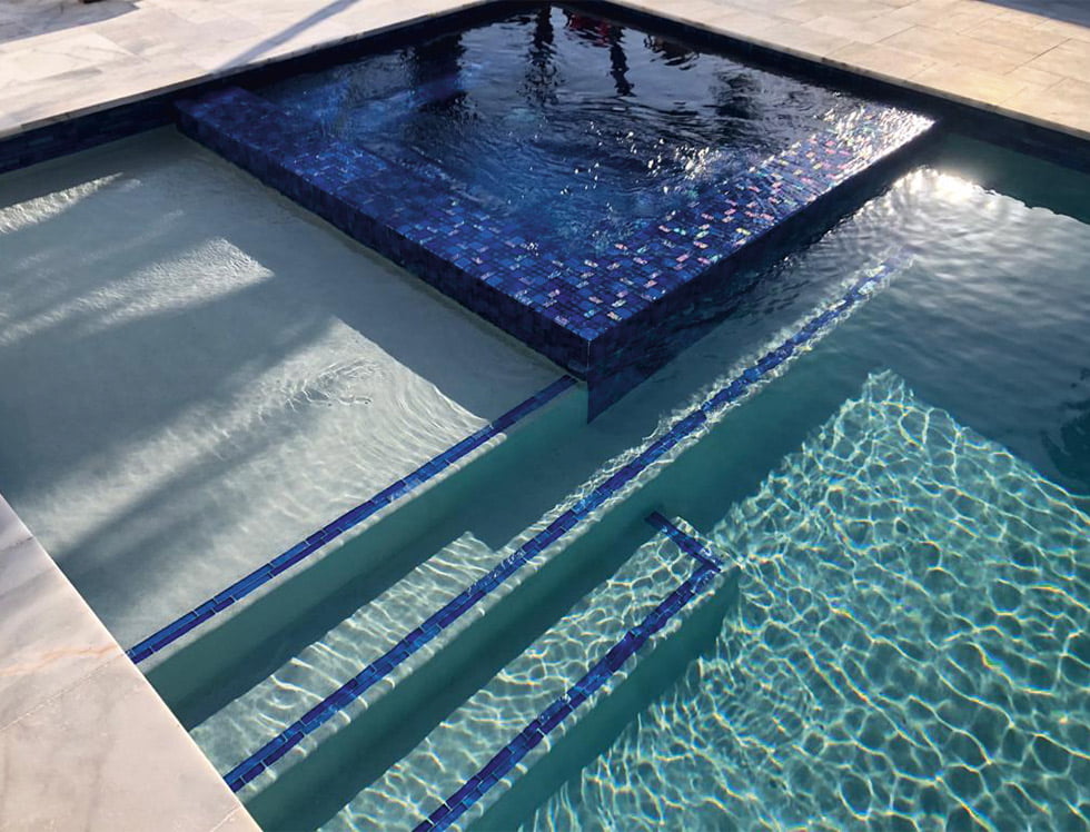 Vibrant glass mosaic tile in a Bahamas-inspired blend of blues and aquas, installed inside a swimming pool for a refreshing, tropical island vibe