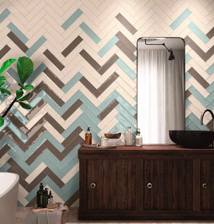 Bathroom wall in a herringbone pattern using multiple colors subway tiles by Mineral Tiles