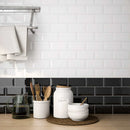 kitchen backsplash featuring a mix of black and white beveled subway tiles in a glossy finish