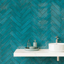 bathroom wall made with teal peacock green subway tiles in a herringbone pattern